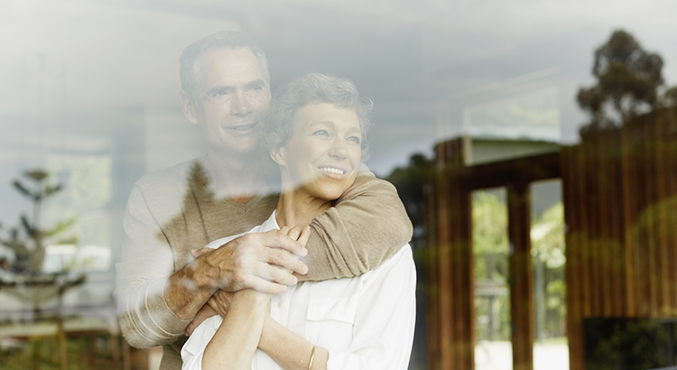 Mature couple looking out through window at home