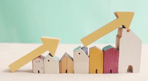 Wooden houses with yellow arrows up. housing boom, property market growing, high demand for real estate, house prices rising concept