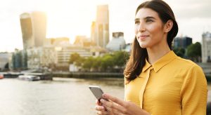 Woman looking up while holding her phone outside