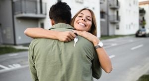 Young couple embracing other in front of their new home
