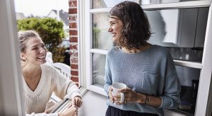 Two happy women talking through the window