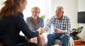 Financial advisor shaking hands with senior man at home