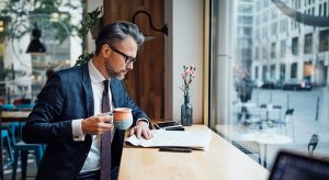 Businessman drinking coffee and reading newspaper at cafe