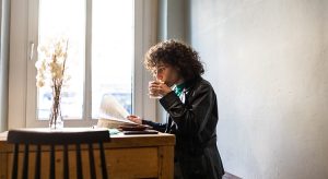 Young lady sipping coffee on her table while reading a paper