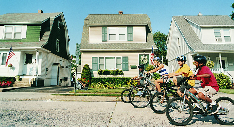 Line of Four Children About To Race Their Mountain Bikes on a Suburban Road in Summer