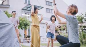 Asian chinese mother giving high-five to her daughter after setup camping tent at backyard of house