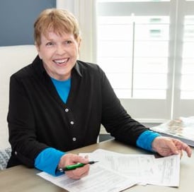 Norma Wall, Broker, North Point Realty, sitting at a desk, paperwork.