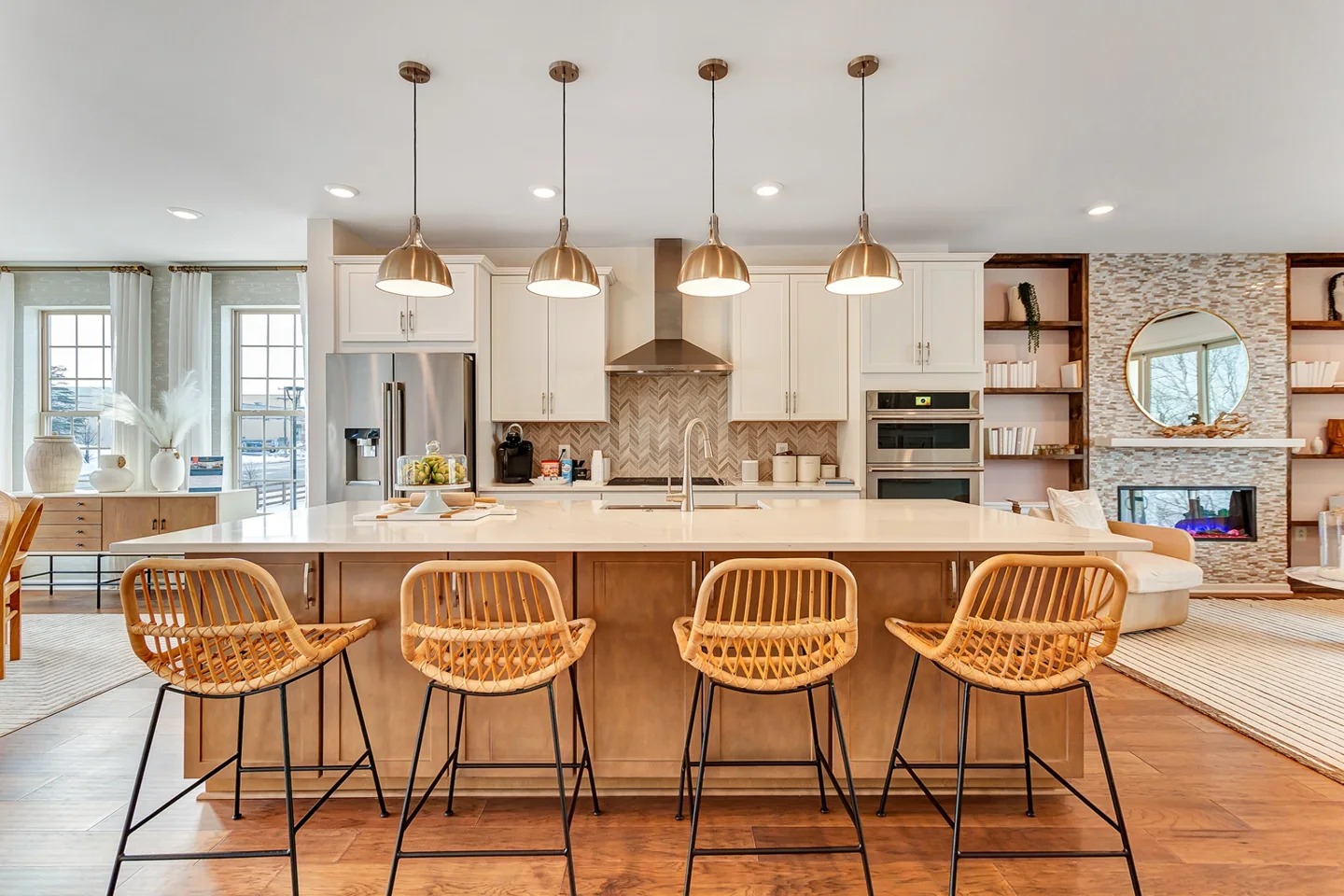 Large model-home kitchen with oversized island, pendant lights, and open-concept family room