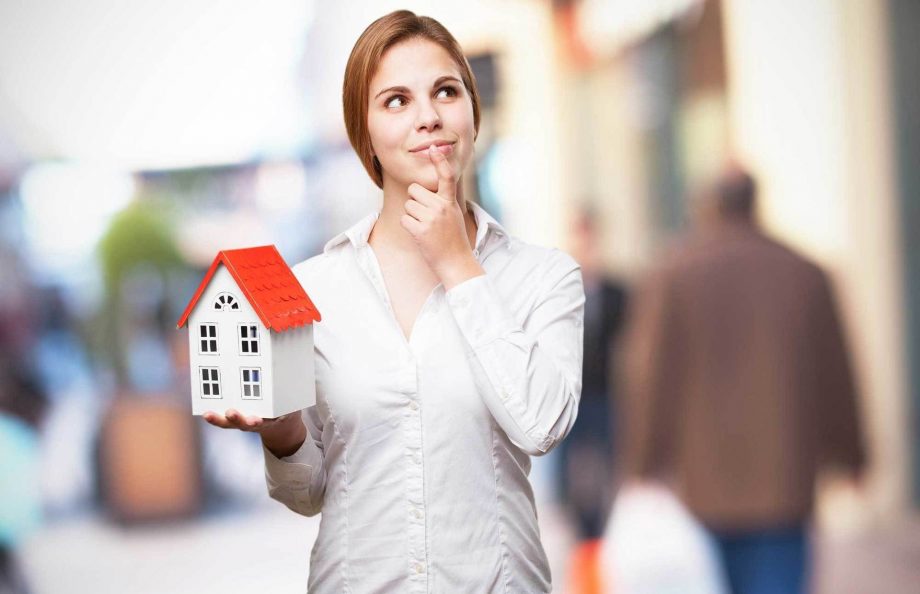 woman holding a model home in thought