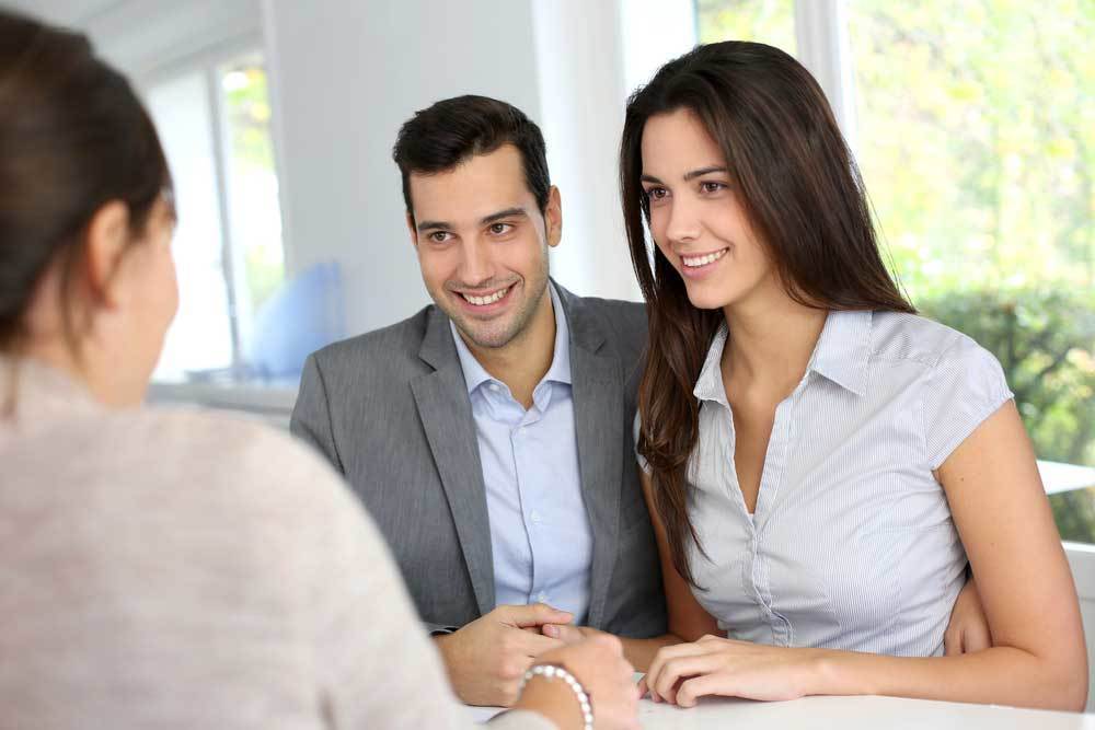 Couple At Desk Talking To Realtor