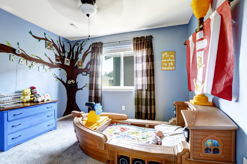 kids blue bedroom with painted tree and ship bed