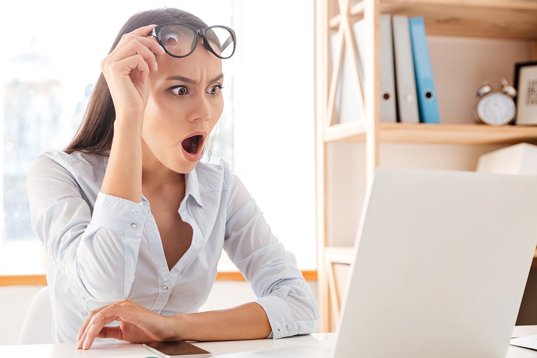 Young woman in white shirt shocking when using laptop