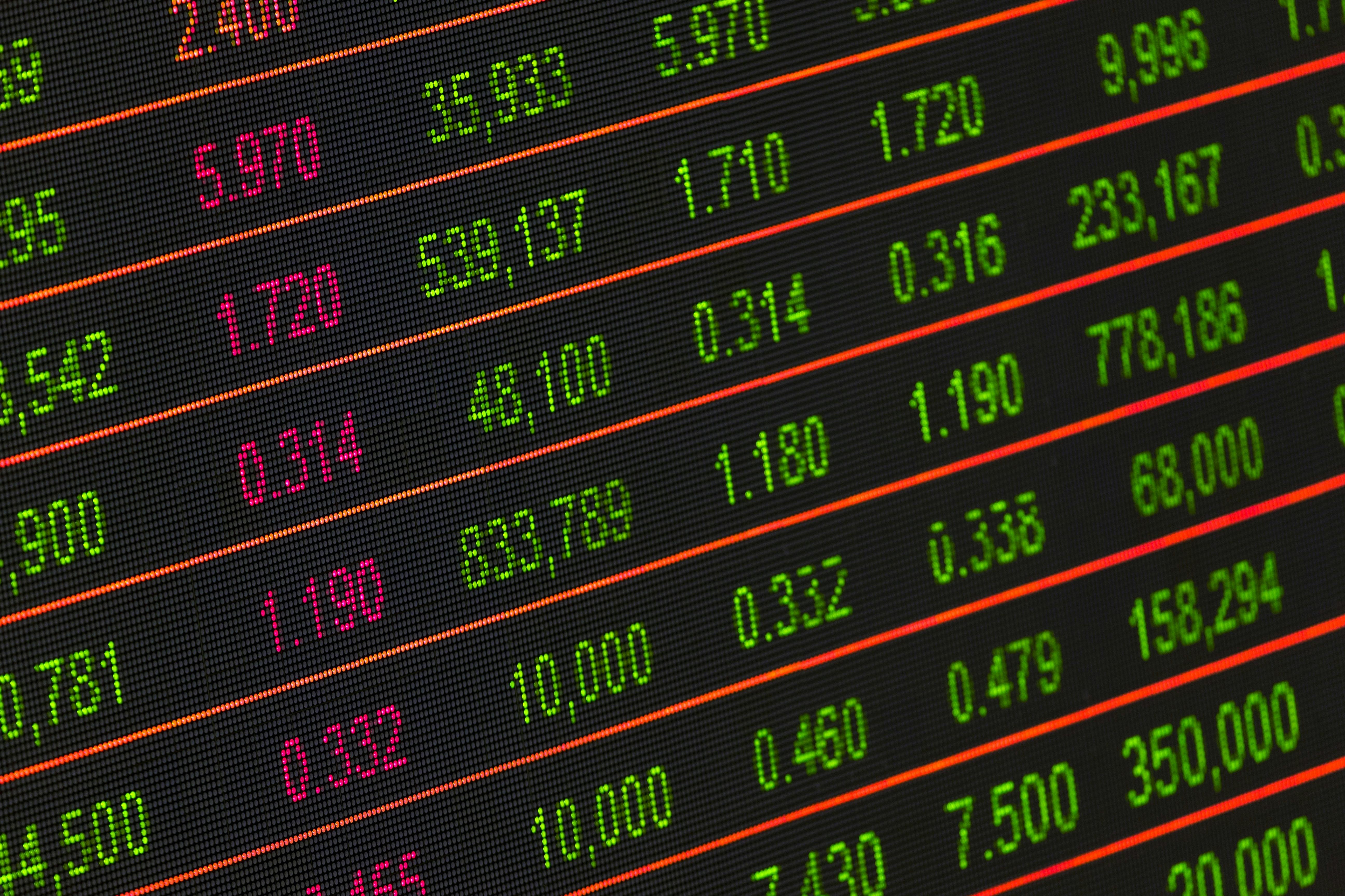 Close-up of a digital stock market display showing various numerical values in green and red, indicating financial data.