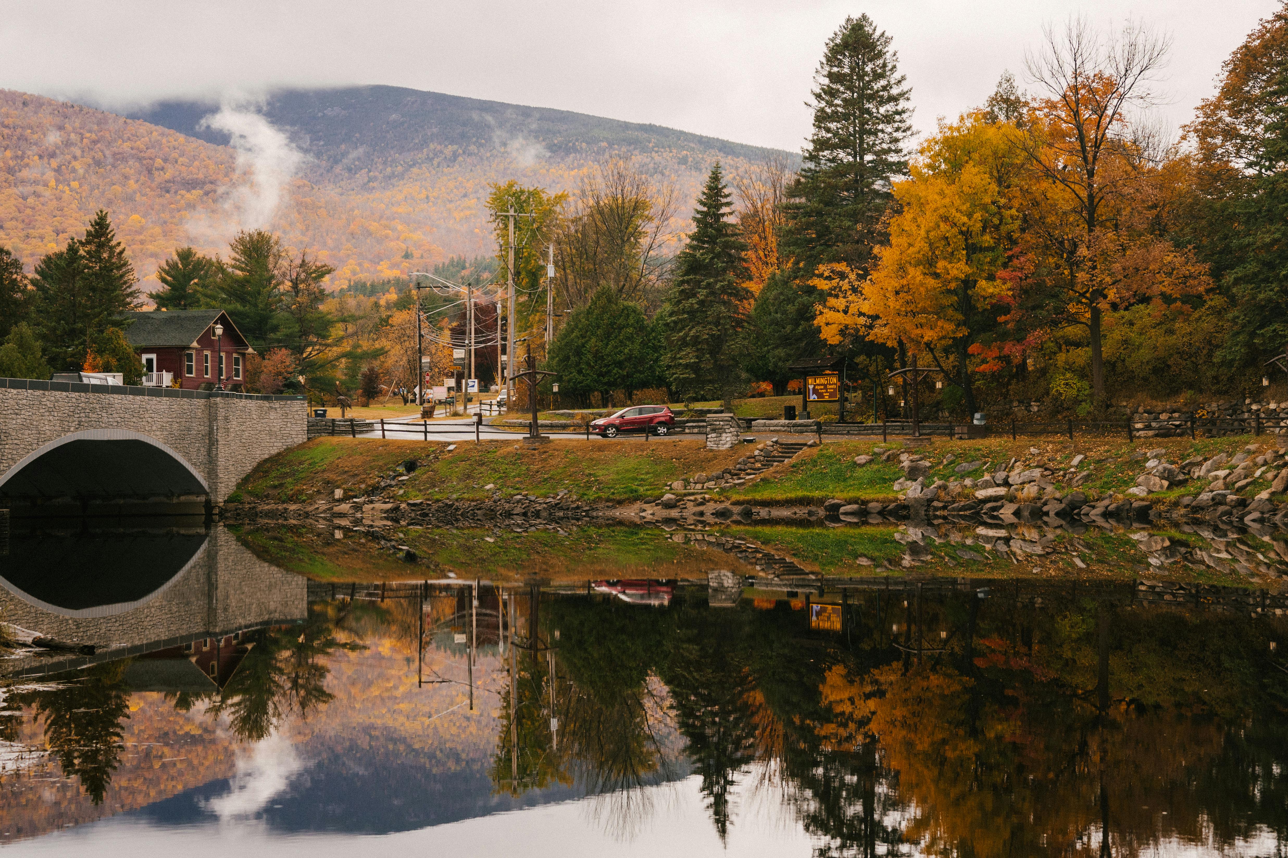 Bridge and trees reflecting in calm river in daytime