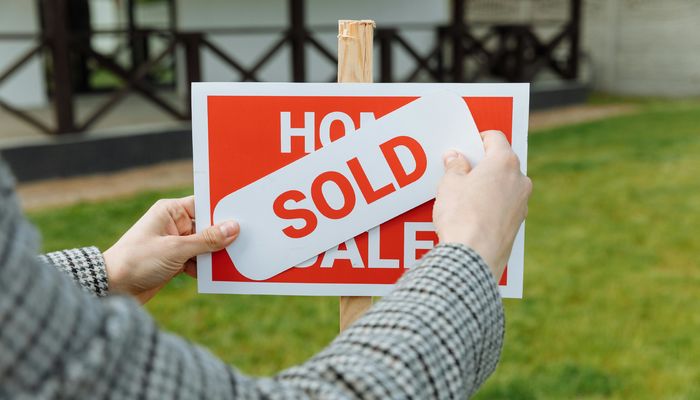 Shallow Focus Photo of a Realtor Posting a Sold Sticker