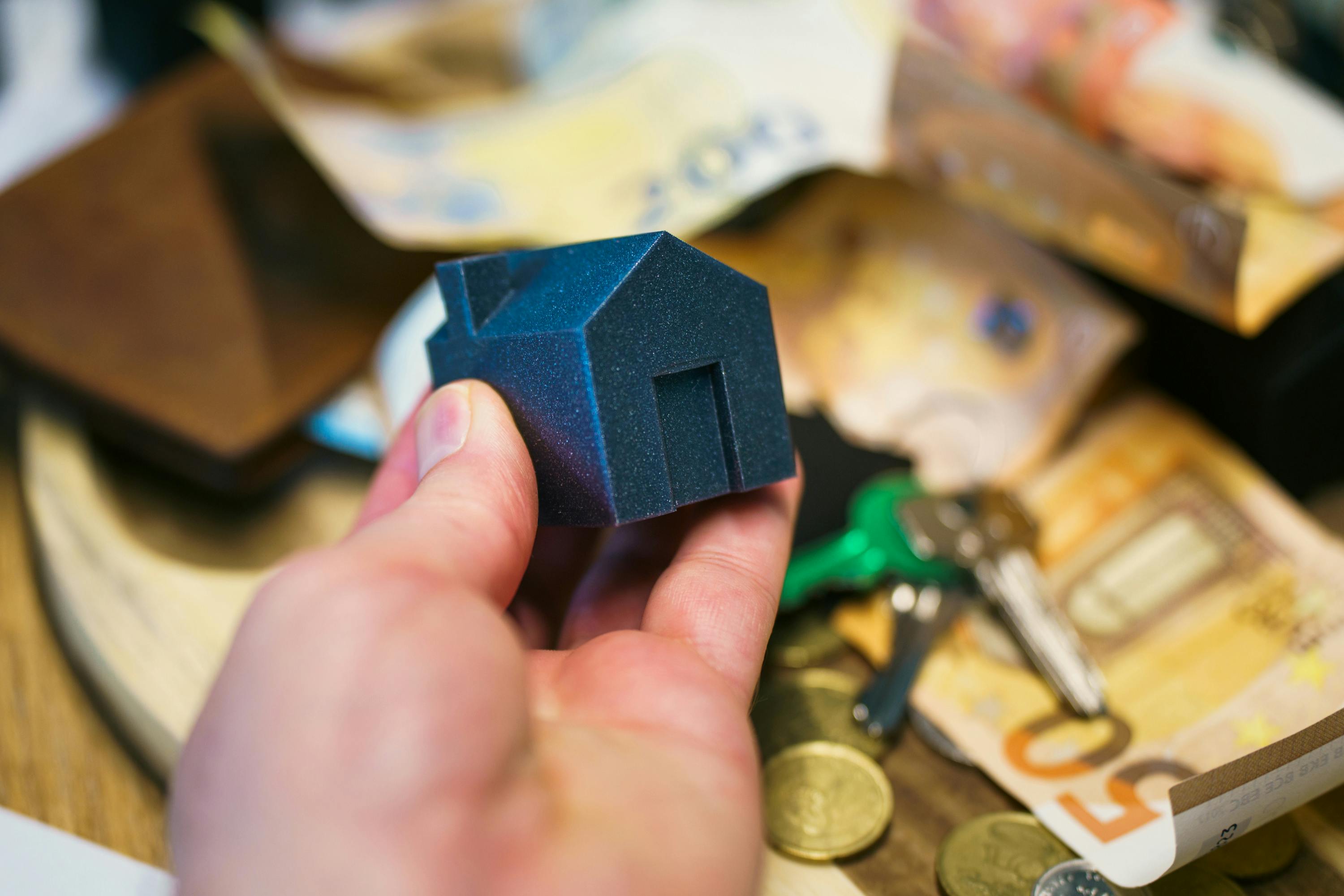 Hand Holding Model House with Money and Keys