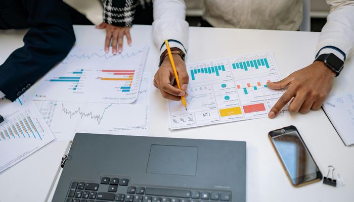 Men and Woman Hands on Table with Papers and Charts