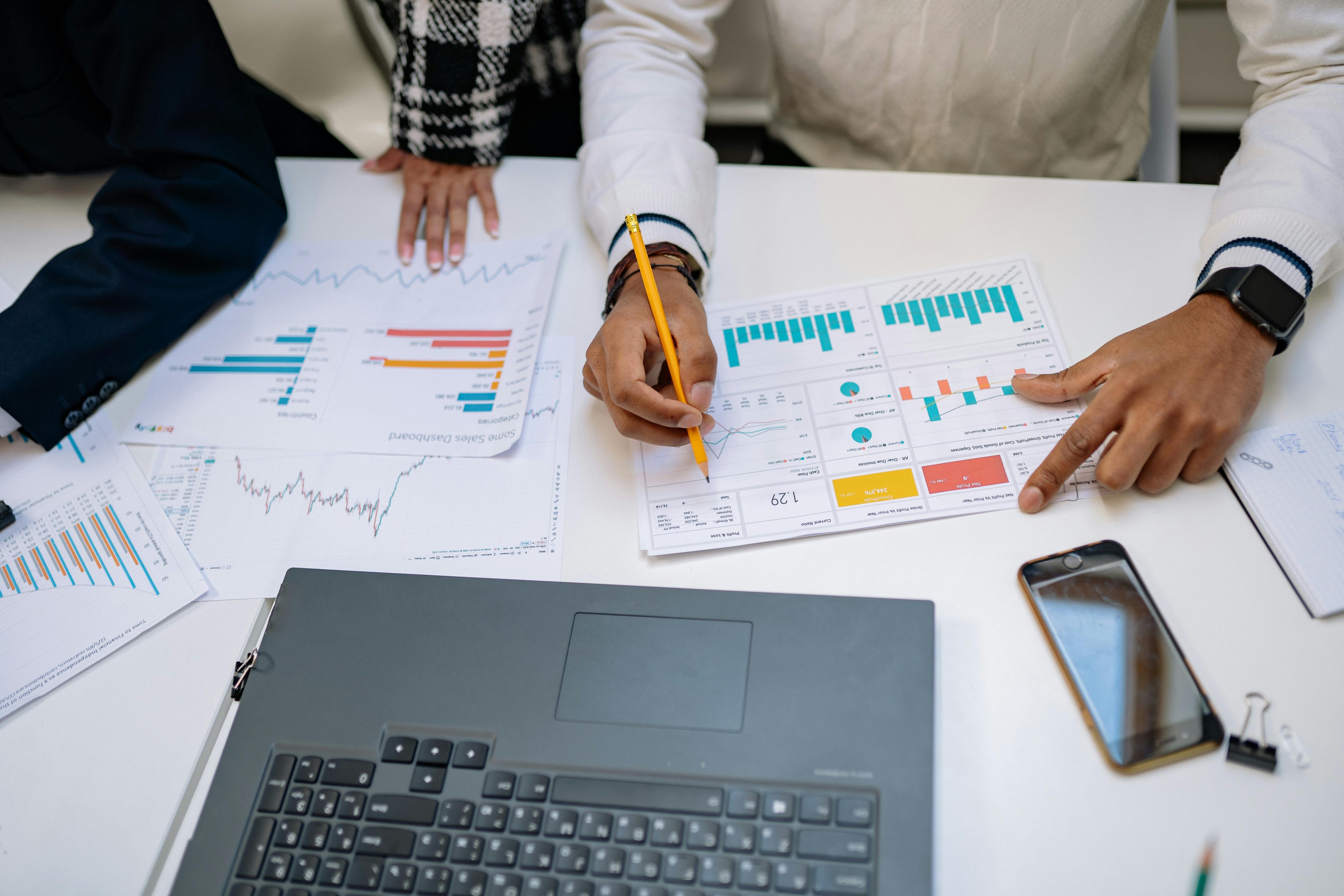 Men and Woman Hands on Table with Papers and Charts