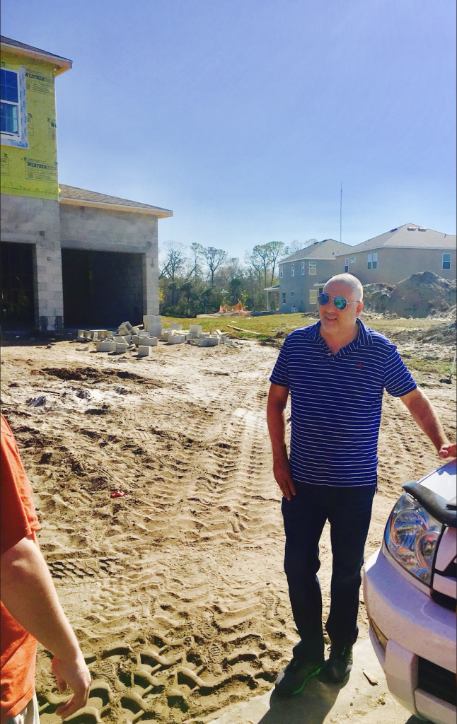 Florida Real Estate 2023 Outlook Aaron Hunt, Team Lead, meets clients at a new build site in St. Petersburg, FL. The picture has bare dirt, a cement block home home shell in the picture.