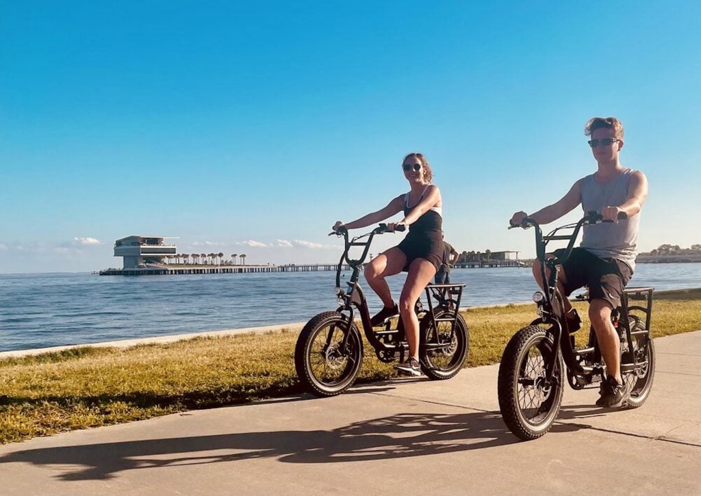 Biking on the waterfront with the St Pete Pier in the background. Why People Are Moving To St Petersburg