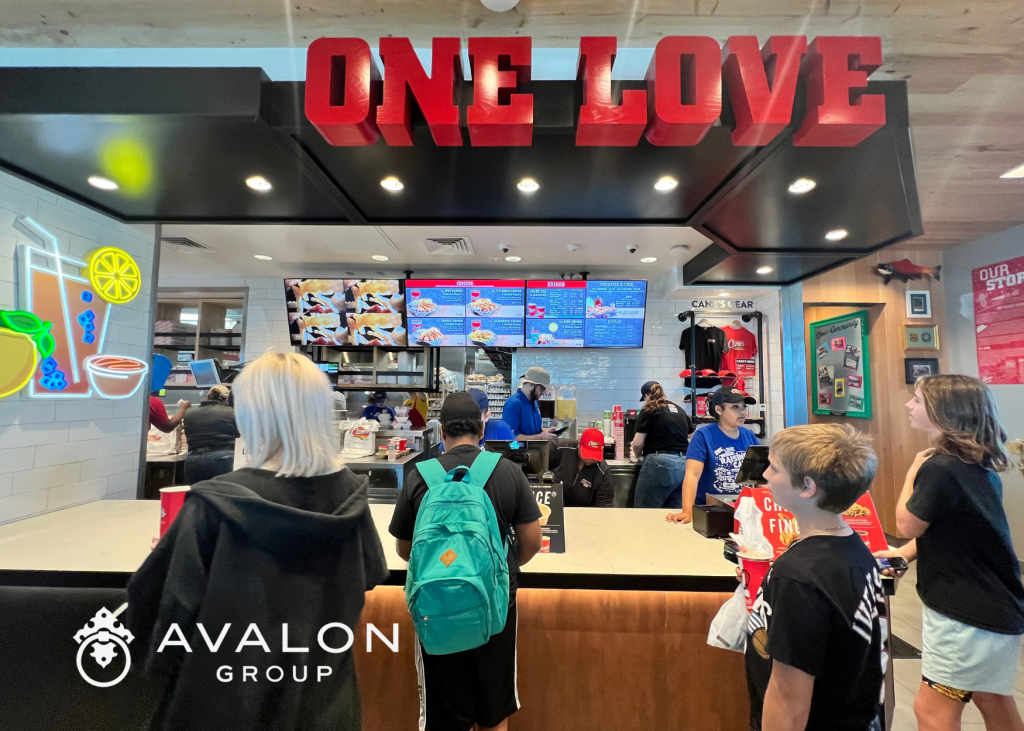 Picture of inside of the "Raising Canes" restaurant in Clearwater FL.  Additionally, the picture shows the front counter with a sign above in red letters that says "One Love."
