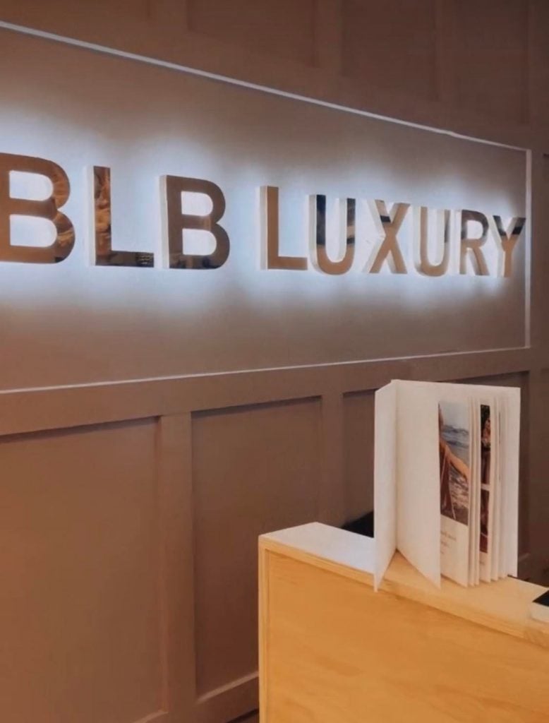 BLB Luxury Front Desk with a silver sign that is backlit with a white light.