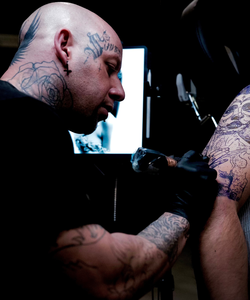Best Place in USA to Invest in Real Estate Christ Jansen Tattoo Artist at work on a tattoo for a client.