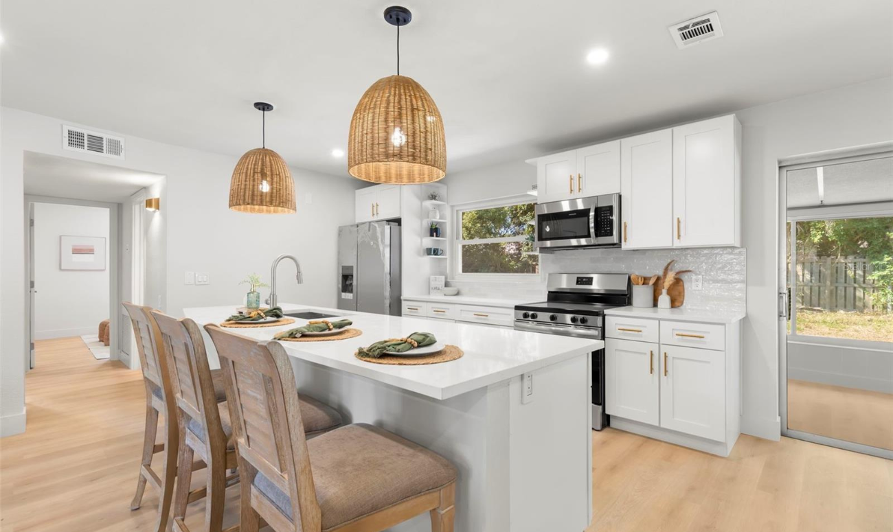 Walls were removed to create an open floor plan with a completely new kitchen. The lighting is made from natural grasses and the counter tops are quartz.