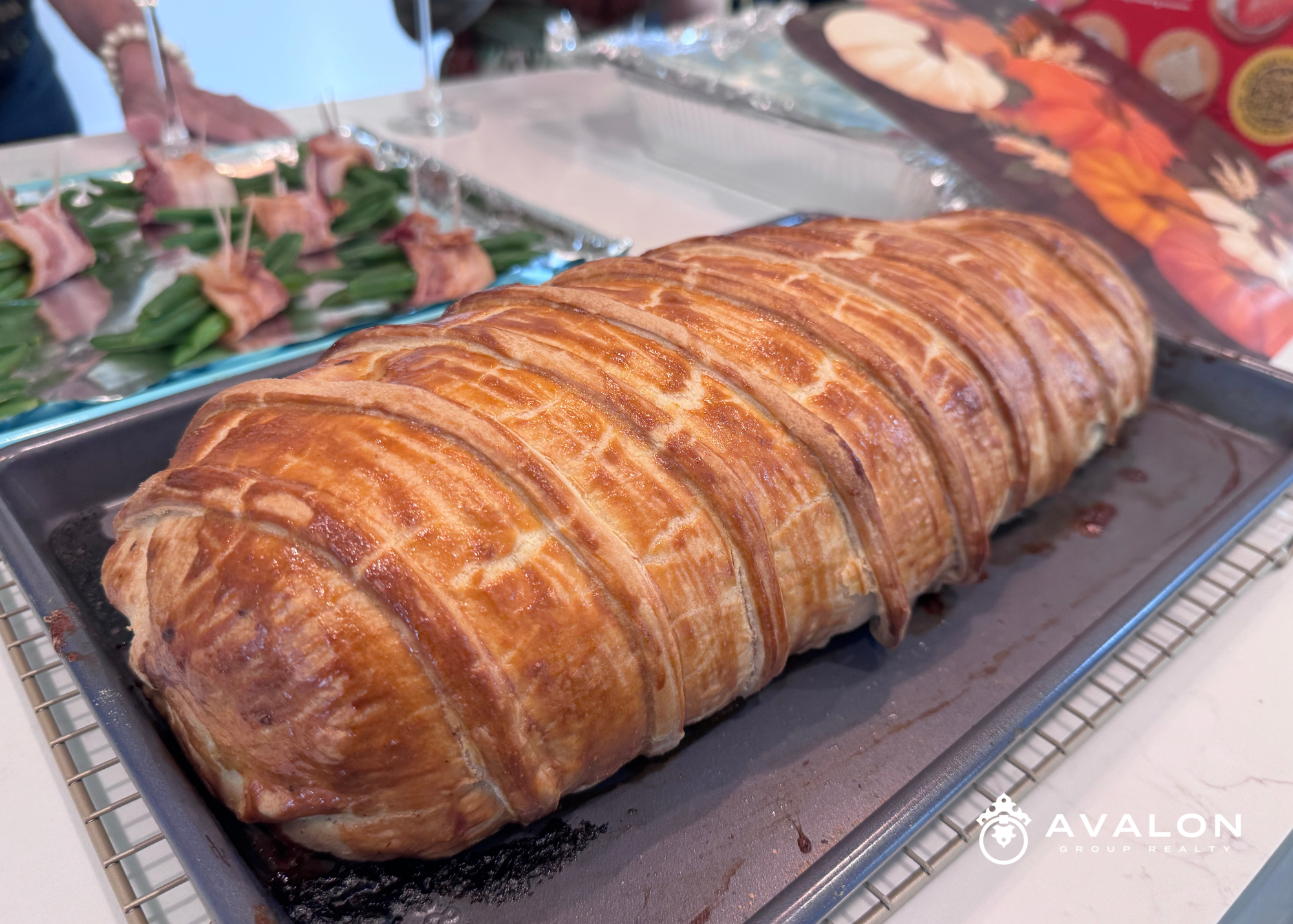 Pre-Thanksgiving Dinner Gift - Beef Wellington is shown in the picture. The puff pastry wrapping the meat is golden brown. There are green beans in the background wrapped with bacon.