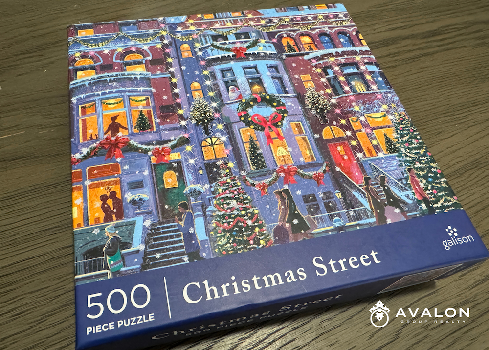 A Christmas puzzle box on a greige wood buffet. The puzzle is a city scene decorated for Christmas