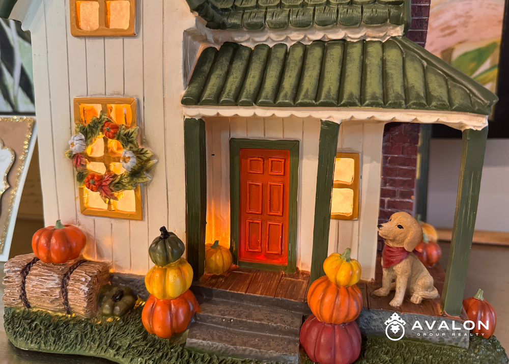 Pre-Thanksgiving Dinner Village house that is white with a green roof. There are Thanksgiving pumpkins on the stairs and wreaths on the windows.