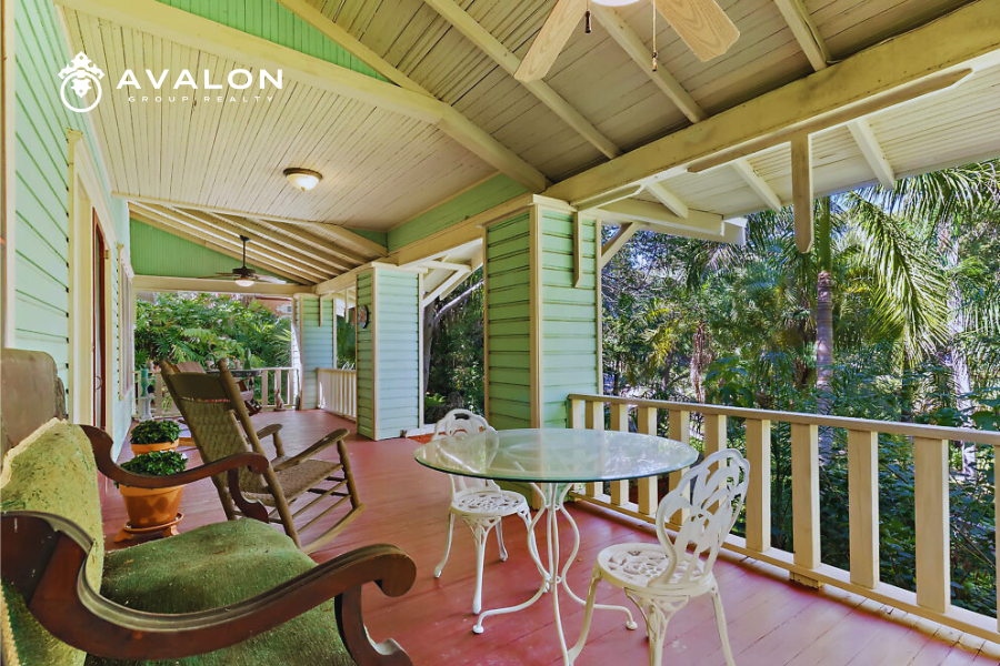 Historic Home Ownership in Kenwood & Old Northeast picture of a large historic front porch with red wood floor, rocking chairs and green siding.