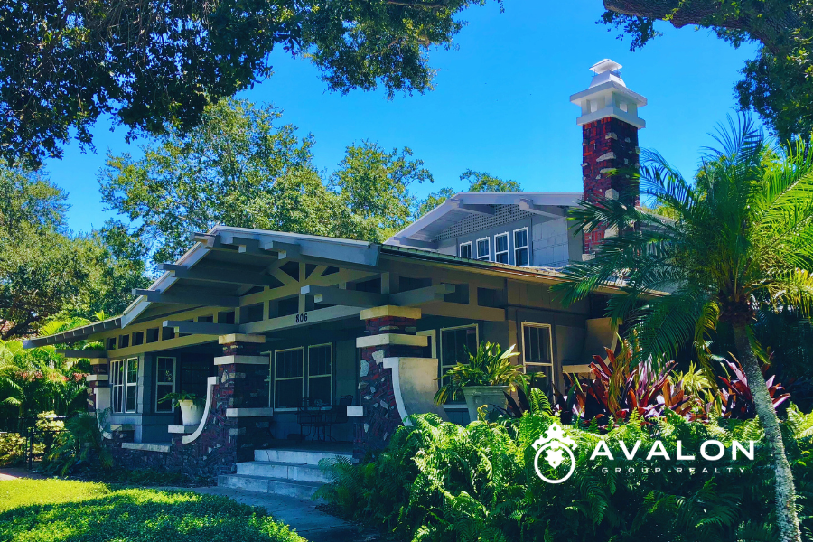 Historic Home Ownership in Kenwood & Old Northeast picture shows a craftsman home with brick fireplace with intermittent stone, and shades of green siding and trim.