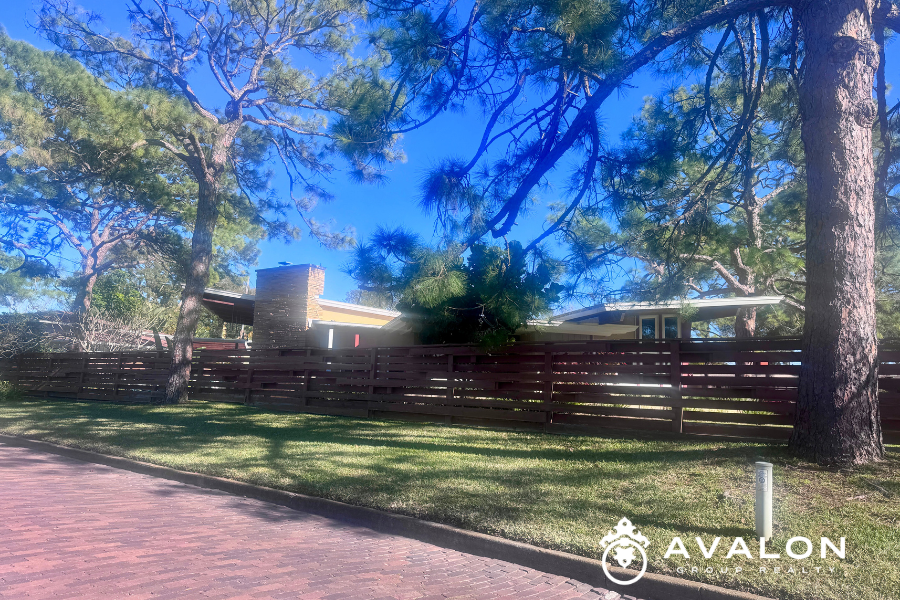 Rear view of an Eagle Crest neighborhood home in St. Petersburg Florida, featuring mature pine trees, brick street, and private fenced yard