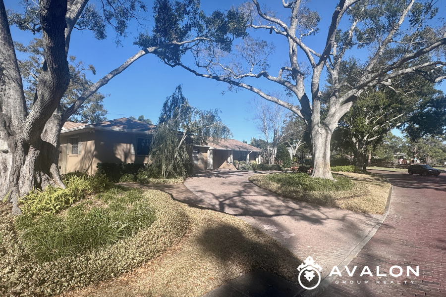Single-story home in the Eagle Crest neighborhood of St. Petersburg Florida with mature oak trees, curved driveway, and brick street