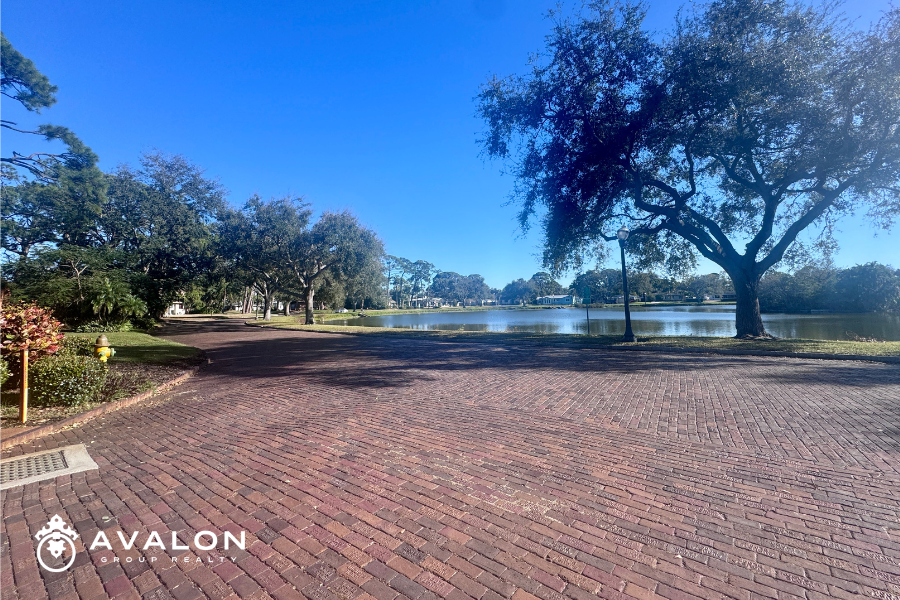 Brick-lined street and spring-fed lake in the Pasadena Lakes neighborhood of St. Petersburg Florida with mature oak trees and waterfront homes