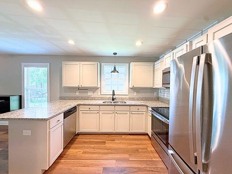 Modern kitchen with granite countertops, white shaker cabinets, stainless steel appliances, and luxury vinyl plank flooring at 521 Johnson Street in Chester SC.