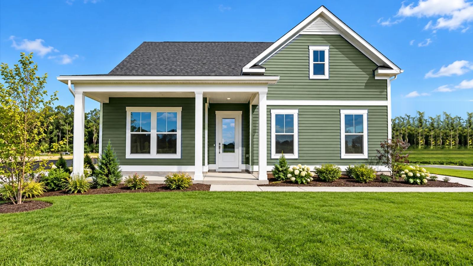 New construction home with green siding and a covered front porch in Sussex County, DE