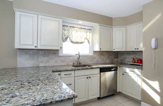 Bright and functional kitchen featuring expansive granite work surfaces, custom cabinetry, tile backsplash, and abundant natural light in a Tottenville Staten Island home.