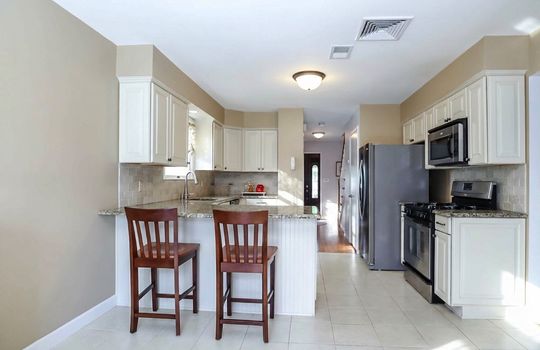 Modern kitchen with granite countertops, stainless steel appliances, breakfast bar seating, and lots of cabinet space.