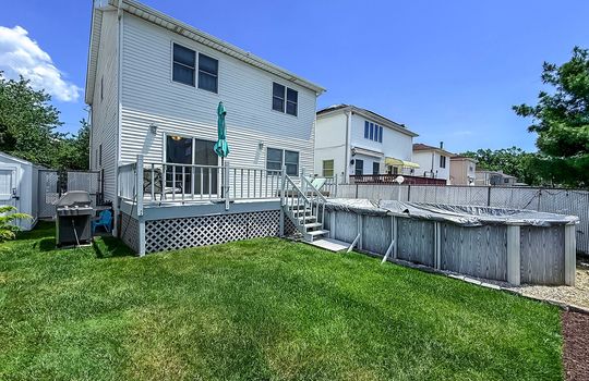 Private fenced backyard with deck, above-ground pool, and green lawn in a Tottenville Staten Island home.