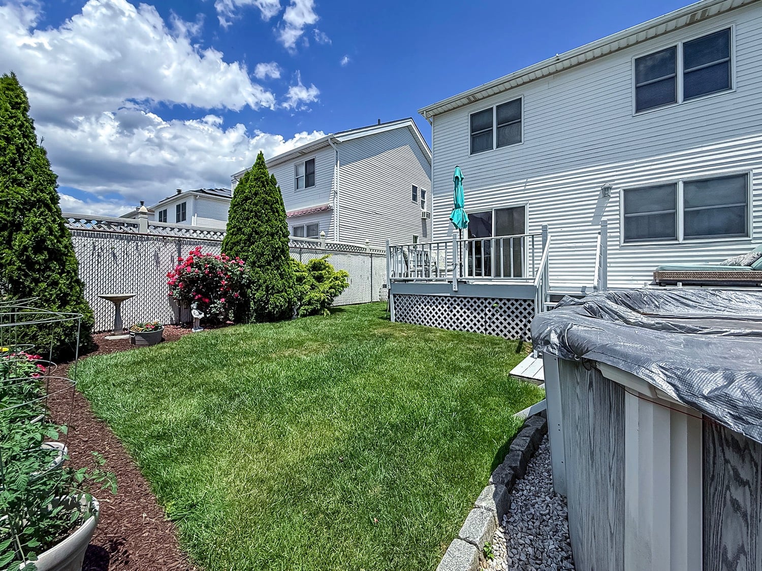 Backyard with deck, above-ground pool, fenced lawn, and outdoor entertaining space in Tottenville