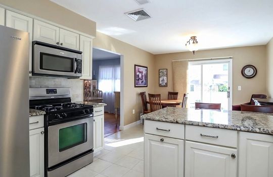Updated eat-in kitchen with granite island, stainless steel appliances, and sliding glass doors leading to the backyard.