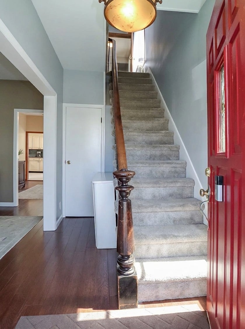 Entry foyer at 34 Church Avenue with a red front door and traditional wood staircase railing.