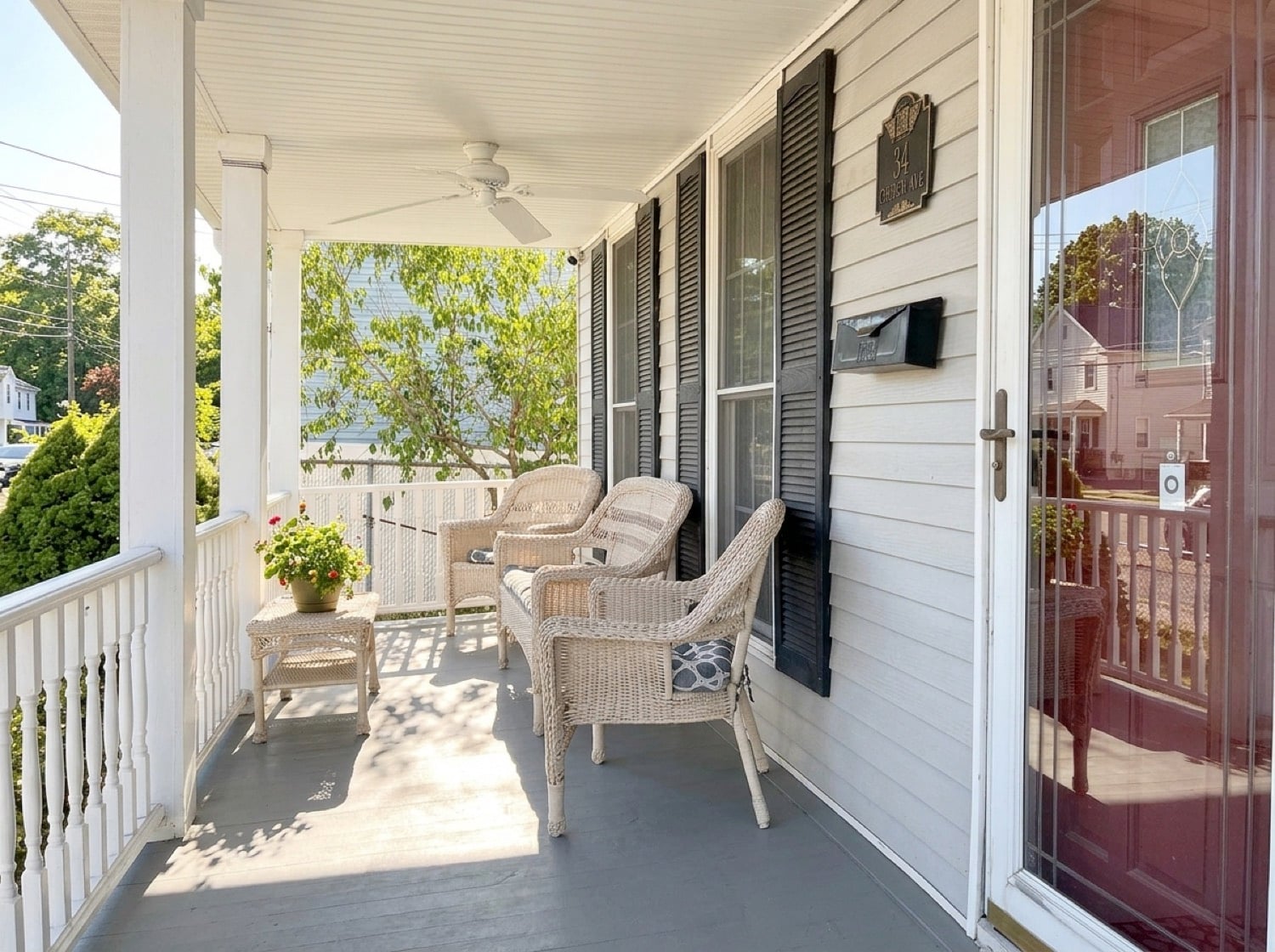 Covered front porch at 34 Church Avenue with wicker seating and white railings.