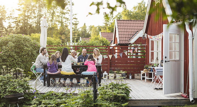 Happy family and friends eating at garden lunch party in back yard