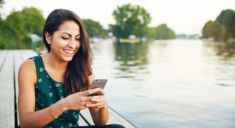 Young woman with smartphone on jetty.