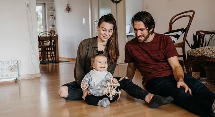 Happy family with baby girl sitting on the floor at home