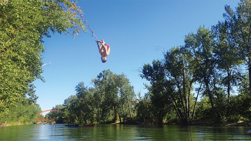 Boy swinging on rope over lake