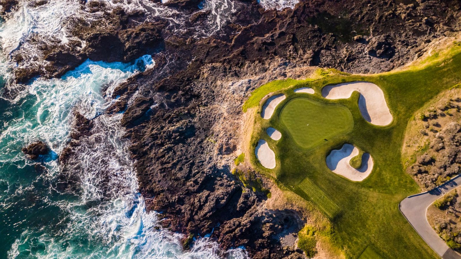 Aerial view of a golf green above the rocky shoreline in Pebble Beach